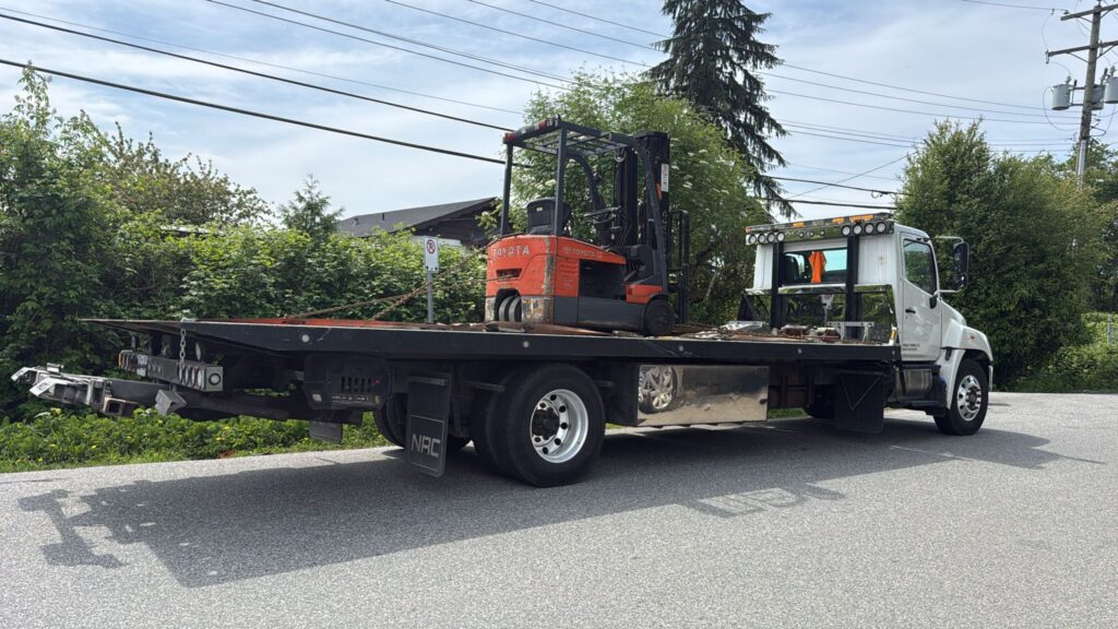 Scrap forklift removal in Vancouver - orange Toyota forklift loaded and secured on a flatbed for pickup