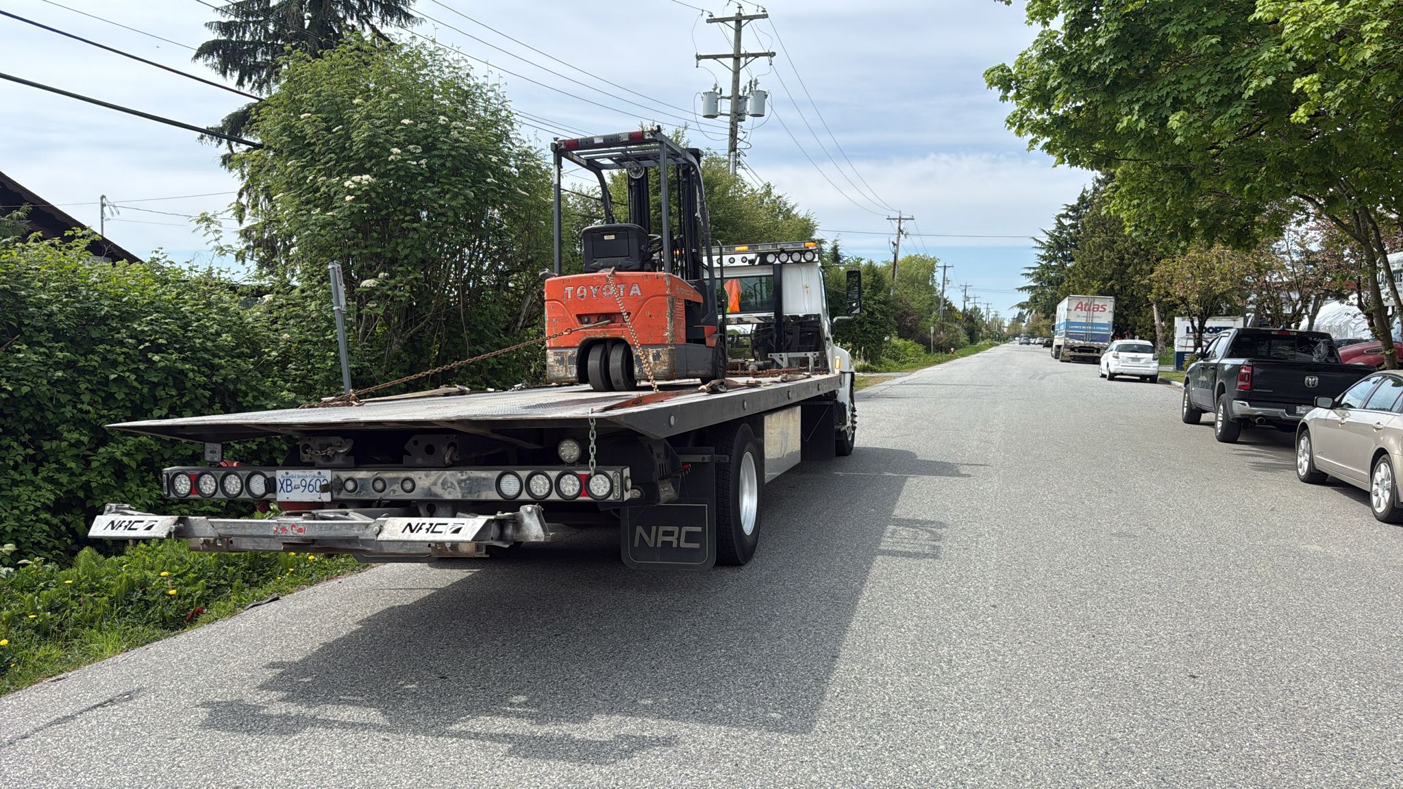 Flatbed truck hauling away an old Toyota forklift during a scrap forklift removal job in Vancouver